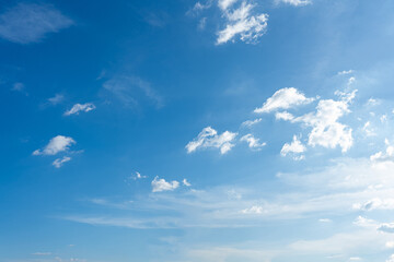Beautiful fluffy white clouds drift across a bright blue summer sky