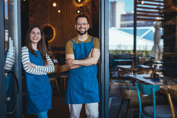 Smiling Café Owners Standing Proudly at Their Restaurant Entrance