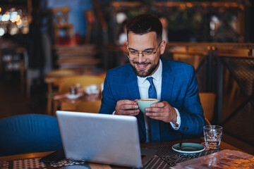 Businessman Enjoying Coffee While Working on Laptop in Café