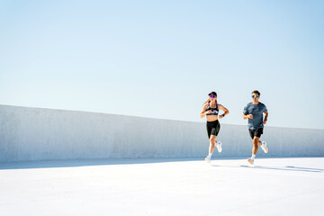 Two Runners Training Together on a Sunny Rooftop During a Clear Afternoon, Enjoying Outdoor...