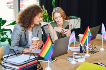 Two coworkers share ideas over coffee while celebrating diversity in the workplace.