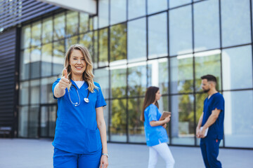 Smiling Medical Professional Giving Thumbs Up Outside Modern Hospital