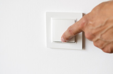 A man's hand turns on the light in the apartment