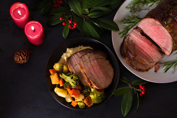 Whole round roast beef and Christmas decorations. New Year dinner table. High angle view