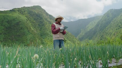 Modern farmer utilizes tablet to inspect scallion growth in field. Smart farming technology enhances crop monitoring. Analyzing plant health for optimal harvest outcomes