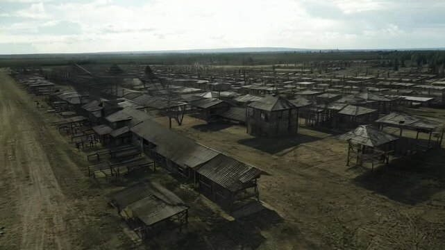 Panning camera view over an abandoned gulag camp with decaying structures and watchtowers