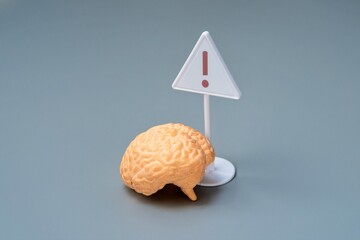 A brain model with a warning sign. Brain health and the potential risks concept.