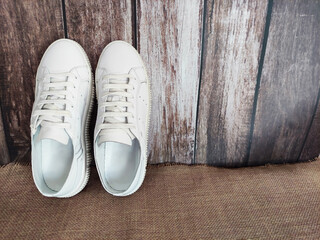 White sports sneakers with laces on a brown fabric jute background