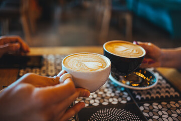 Hands Holding Cappuccinos in Cozy Cafe Setting