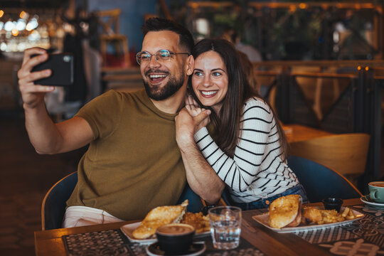 Happy Couple Enjoying Lunch and Taking Selfie at Cafe