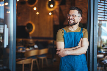 Smiling Cafe Owner Standing at the Entrance of Modern Coffee Shop