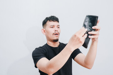 a portrait of asian young man holding his empty wallet with sad expression