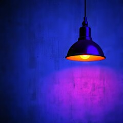 Obraz premium A modern pendant light casts a warm glow against a textured blue wall.