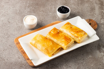 Thin pancakes stuffed with cottage cheese served with sour cream and black currant jam. French crepes. 
