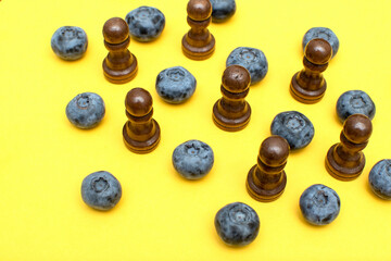 Black wooden chess pawns and blueberry	