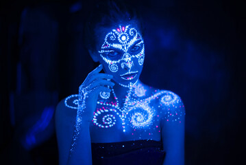 Body art on the body and hand of a girl glowing in the ultraviolet light.