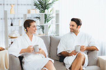 Fototapeta premium Beauty or body treatment spa salon vacation lifestyle concept with couple wearing bathrobe relaxing with drinks in luxurious hotel spa or resort room. Vacation and leisure relaxation. Quiescent