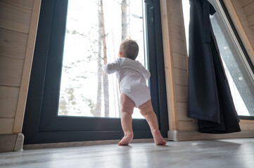 Baby boy standing by the patio window. 