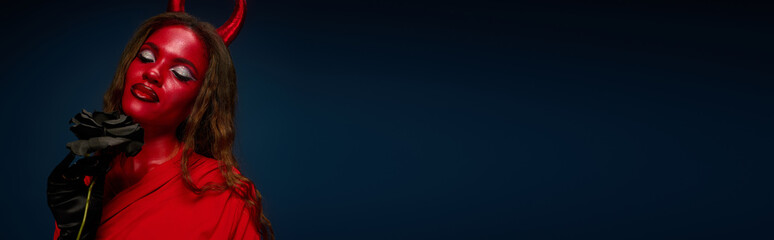 A captivating woman dressed in a devil costume exudes Halloween charm with bold makeup.