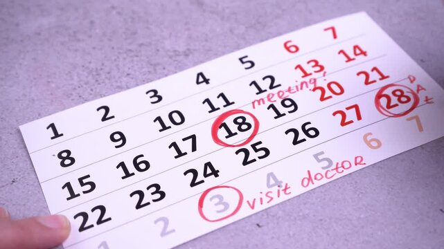 Plan a work week. Circle and strike through calendar dates. Write with a red marker. Hand planning dates. Visit doctor