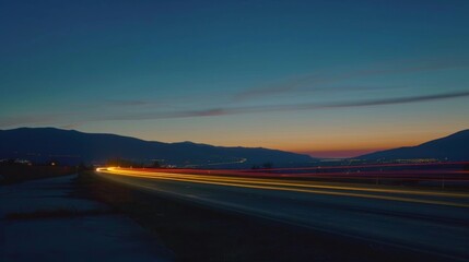 Fototapeta premium As the sun sets over the horizon the mountain range comes to life with dazzling car light trails.