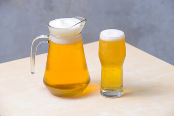Beer in a glass draft beer pitcher on the wooden table.