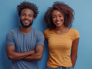 Obraz premium Two people smiling against a solid blue background, showcasing joyful expressions and casual outfits.