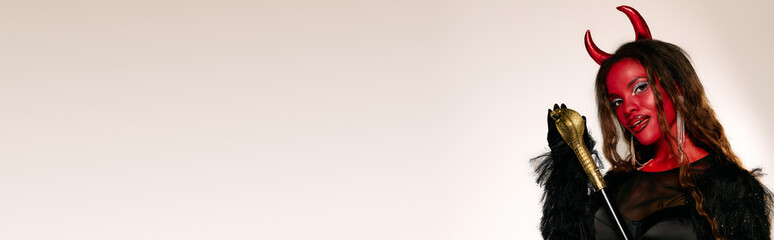 A beautiful woman dressed as a devil showcases her stunning Halloween costume, ready for fun.