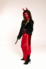 A vibrant Halloween celebration features a woman in a striking devil costume, complete with horns.
