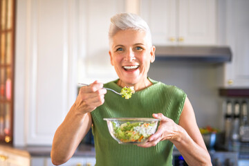 Mature smiling woman eating salad, fruits and vegetables.