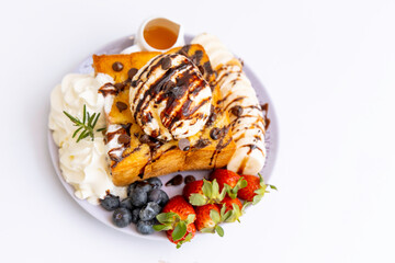 cake with chocolate,Honey toast on a plate with sweet fruits, blueberries, strawberries and bananas on wooden table.A delicious dessert with ice cream and toast. It is popular with Thai people.