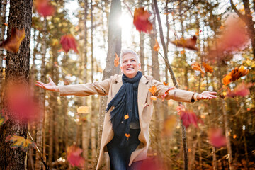 Mature woman in autumn forest, dressed in cozy fall attire, Reflection and connection with nature,...