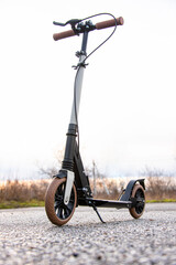 A scooter stands on the asphalt during sunset. Vertical photo.