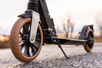 A scooter stands on the asphalt during sunset.