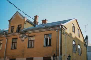 an ancient yellow building with brown windows in the center of a European city on a sunny day