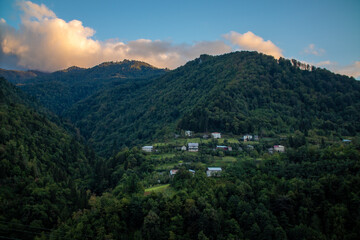 A valley with mountains and trees, featuring a village in front