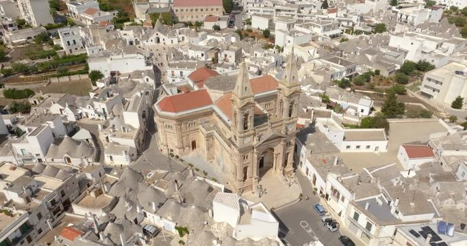 Aerial view of the parish church of Saints Cosmas and Damian located in Alberobello, a small town in the metropolitan city of Bari in Puglia, Italy. Above the facade rise the two twin bell towers.