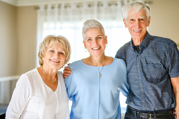 Happy daughter embracing her two elderly parents at living room. Love and care.