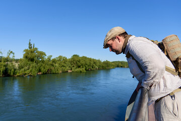 Young man looks out over the Neuquen River from a lookout point. Connection with nature in the city during springtime.