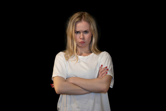 Annoyed Young Woman with Arms Crossed and Angry Expression in White T-shirt on Black Background