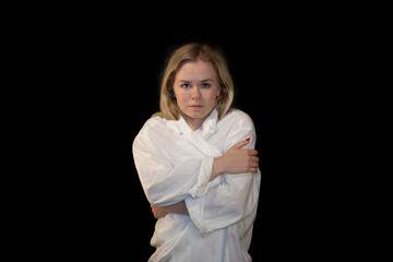 Young woman embracing herself in isolation, feeling cold and vulnerable