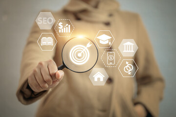 A person is holding a magnifying glass over a screen with various icons