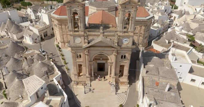 Aerial view of the parish church of Saints Cosmas and Damian located in Alberobello, a small town in the metropolitan city of Bari in Puglia, Italy. Above the facade rise the two twin bell towers.