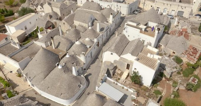 Aerial view of a empty street among the trulli of Alberobello, in the metropolitan city of Bari in Puglia, Italy. They are ancient traditional white houses with a conical roof. Holiday destination.