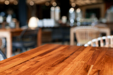 A close-up of a rustic wooden table in a cozy restaurant with blurred background. Perfect for concepts of hospitality, dining ambiance, and interior decor.