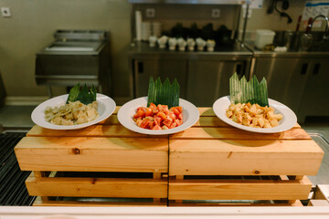 Three food displays on plate featuring tomatoes, potatoes, and vegetables arranged on wooden boards