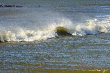 Breaking waves with the seaspray being blown back in Sturmvogelbucht, Namibia.