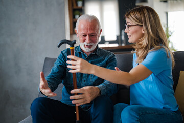 Smiling Elderly Man Assisted by Caring Woman at Home