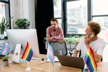 A couple collaborates in a vibrant office adorned with pride flags, celebrating creativity.