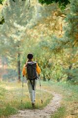 A young African American woman enjoys a peaceful hike in a colorful autumn forest, surrounded by nature beauty.